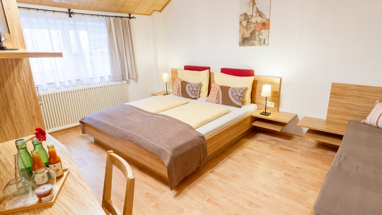 Gästezimmer, © Annemarie Heller Gemütliches Gästezimmer mit Doppelbett, Holzmöbeln und Dekoration.