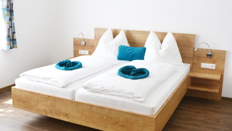 Gästezimmer, © Familie Martin Modernes Gästezimmer mit Doppelbett, weißen Bettdecken und blauen Kissen.