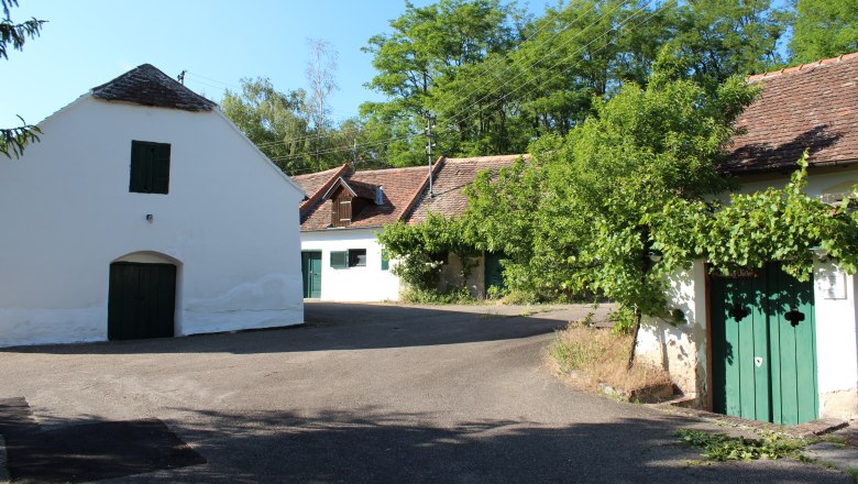 Untermarkersdorf Kellergasse, © Weinviertel Tourismus Traditionelle Weinkeller in einer ländlichen Umgebung mit Bäumen und blauem Himmel.