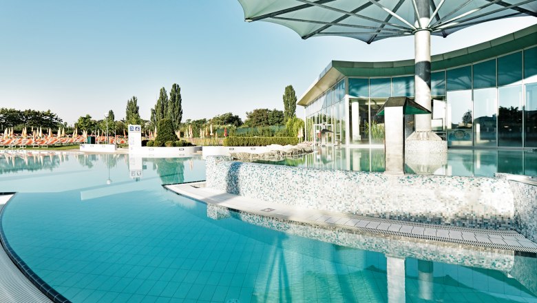 Außenbereich der Therme Laa, © Therme Laa Außenbereich der Therme Laa mit Pool und Sonnenschirmen.