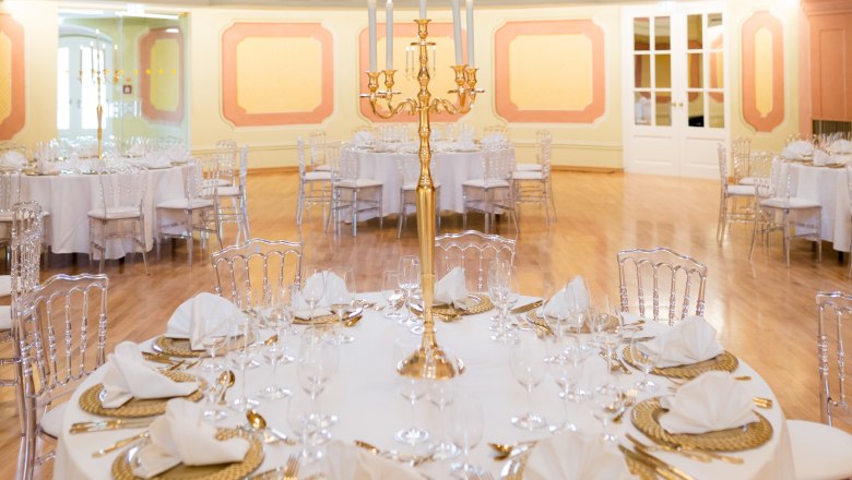 Conference Center Laxenburg, Theatersaal, © Conference Center Laxenburg Eleganter Theatersaal mit runden, festlich gedeckten Tischen und goldenen Kerzenhaltern.