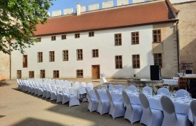 Tafeln im Weinviertel, © Weinviertel Tourismus GmbH Langer Tisch mit weißen Stühlen in einem historischen Innenhof.