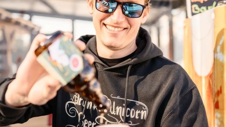 TDR-Inhaber, © Drunken Unicorn Beer Factory Mann mit Sonnenbrille und Mütze schenkt Bier aus einer Flasche in ein Glas ein.