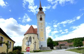 Schiefer Turm von Waitzendorf, © Weinstraße Weinviertel Kirche mit schiefem Turm in Waitzendorf, umgeben von blauen Himmel und Wolken.