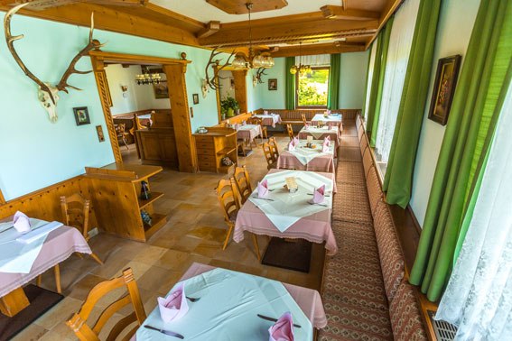 Gut speisen im Bruckerhof, © Wiener Alpen / Christian Kremsl Gemütliches Restaurant mit Holzmöbeln und Tischdecken, dekoriert mit Geweihen an den Wänden.