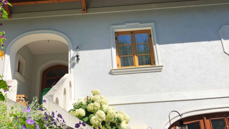 Weinbau Sandbichler, © Donau Niederösterreich Haus mit weißen Wänden, Holzdach und Blumen im Vordergrund.