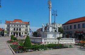 td-hauptplatz-mit-bezirksberichtzehetmayer, © DNÖ Zehetmayer Hauptplatz mit barocker Säule und Blumenbeeten, im Hintergrund ein historisches Gebäude.