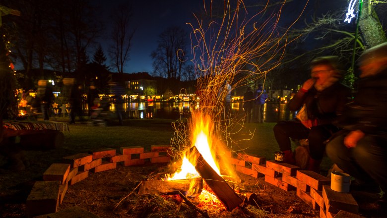 Aspanger Adventmarkt am Teich, © wieneralpen-kremsl Lagerfeuer am Aspanger Adventmarkt mit Menschen im Hintergrund.
