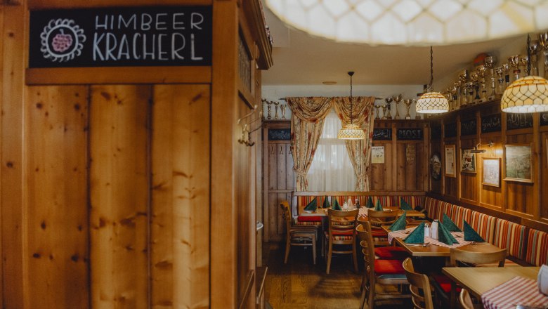 Urige Bauernstube, © Niederösterreich Werbung/Rita Newman Gemütliche Bauernstube mit Holzmöbeln, karierten Tischdecken und Pokalen auf einem Regal.