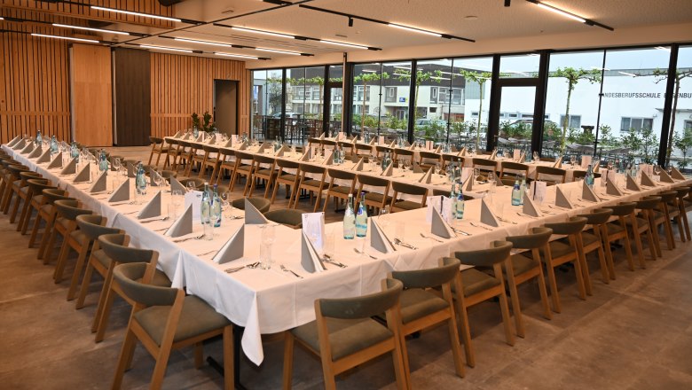 Seminarraum, © EGINO-Premium Hotel, Restaurant & Bar Ein großer, moderner Seminarraum mit gedeckten Tischen in U-Form, Holzstühlen und großen Fenstern.