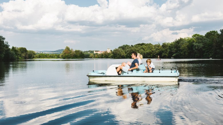 Tretbootfahren am Donausee in Weitenegg, © NÖW_Stefan Fürtbauer Familie auf einem Tretboot auf einem See mit bewölktem Himmel.