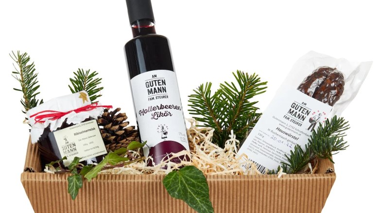 Geschenkorb vom Mostheurigen Steurer, © Mostheurigen Steurer Geschenkkorb mit Likör, Marmelade und Wurst, dekoriert mit Tannenzweigen.