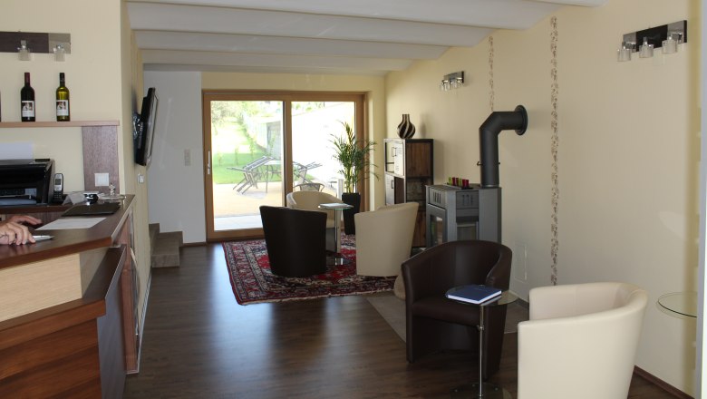 Gästehaus Woditschka, © Fam. Woditschka Innenansicht eines modernen Gästehauses mit Sitzbereich, Kamin und Glastür zum Garten.