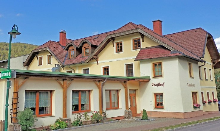Großzügige Räume und Gastgarten für Feste, © Wiener Alpen Ein traditioneller Gasthof mit gelber Fassade und roten Dächern.