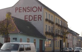 Pension Eder, © Evelyn Kunz Straßenszene mit der Pension Eder und vorbeifahrenden Autos.