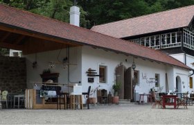 Hauser's Hölzelmühle, © Fam. Hauser Ein traditionelles Gebäude mit rotem Ziegeldach und Holzelementen, umgeben von Bäumen.