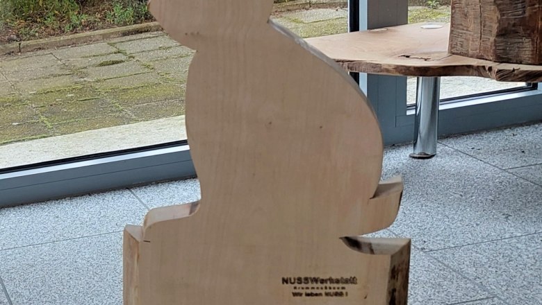 fruehlingseinzug-2, © Johann Peham Holzfigur eines Hasen vor einem Fenster mit Blick auf einen Garten.