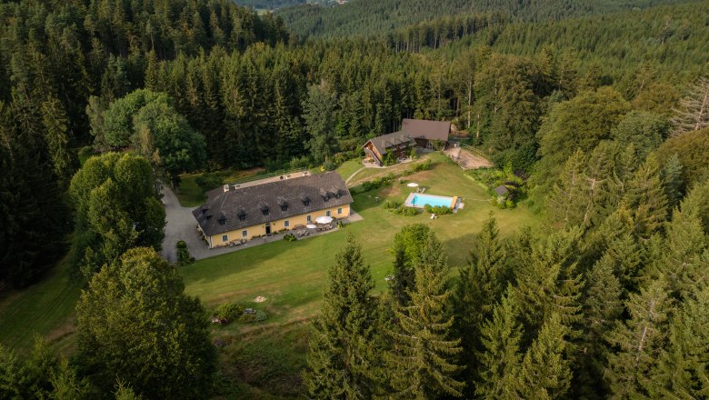 Forsthaus Langschlägerwald, © Niederösterreich Werbung / Maximilian Pawlikowsky Luftaufnahme eines Forsthauses inmitten eines dichten Waldes mit angrenzendem Pool und Wiese.