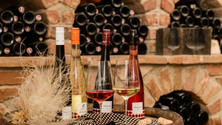 Gritsch, © Best of Wachau/Rita Newmann Weinflaschen und Gläser vor einem Regal mit Weinflaschen in einem Weinkeller.