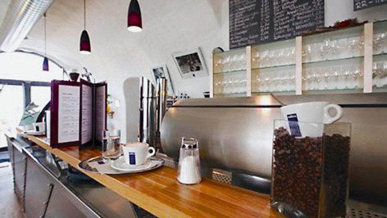 Café & Wein im Ursin Haus, © Ursin Haus Innenansicht eines Cafés mit Theke, Kaffeemaschine und Gläsern.