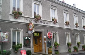 Gasthof Wieser, © zVg Fassade des Gasthofs Wieser mit Blumenkästen und Werbeschildern.