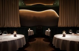 Restaurant, © Laura Thiesbrummel Elegantes Restaurant mit runden Tischen, weißen Tischdecken und gedämpfter Beleuchtung.