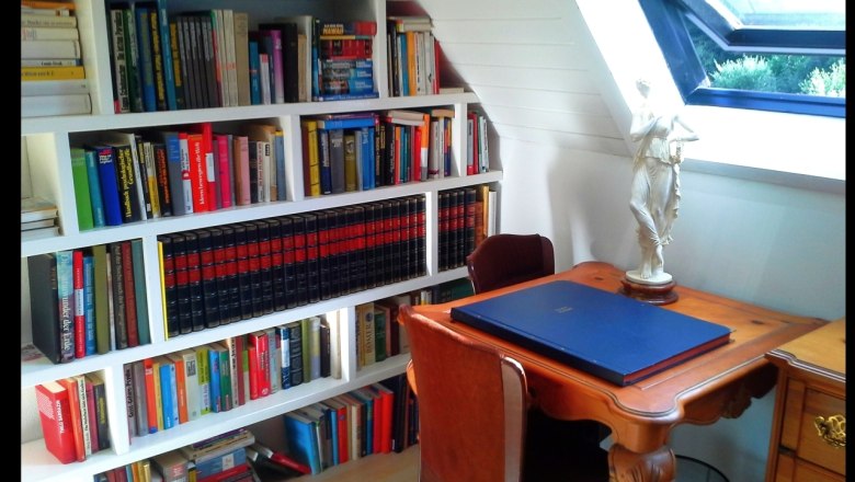 Roomantic Apartments, © Roomantic Apartments Ein gemütlicher Arbeitsbereich mit Bücherregal, Schreibtisch und Statue.