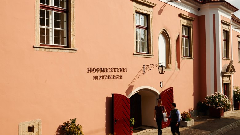 Hofmeisterei in der Weltkulturerberegion Wachau, © Hofmeisterei Hirtzberger/Julius Hirtzberger Historisches Gebäude der Hofmeisterei Hirtzberger mit rosa Fassade und roten Türen in der Wachau.