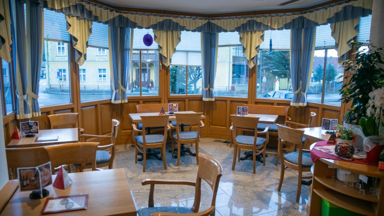 Gemütliche Kaffeepausen., © Koll GmbH Innenansicht eines gemütlichen Cafés mit Holzmöbeln und großen Fenstern.