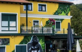 Johnys Jungle, © Johnys Jungle Gelbes Gebäude mit Gorilla-Wandgemälde und Dschungelmotiven.