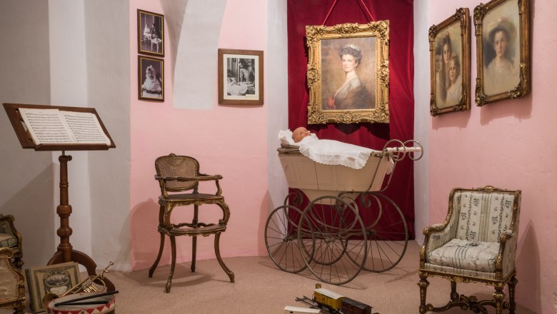 Kinderzimmer im Museum, © Schloss Artstetten Historisches Kinderzimmer im Museum mit antikem Kinderwagen, Stühlen und Spielzeugzug.