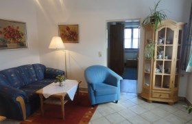 Haus König, © Fam. König Wohnzimmer mit blauer Couch, blauem Sessel, Holztisch und Vitrine.