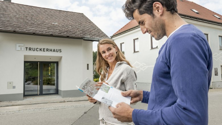 Das Truckerhaus, © Waldviertel Tourismus, Studio Kerschbaum Zwei Personen vor dem Truckerhaus, die Broschüren lesen.