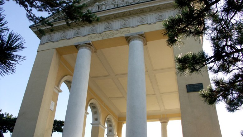 Husarentempel, © Husarentempel Der Husarentempel mit Säulen und Reliefs, umgeben von Bäumen.