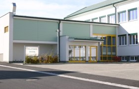 Hallenbad Dobersberg, © Gemeinde Dobersberg Außenansicht des Hallenbads Dobersberg mit gelben Türen und Fenstern.