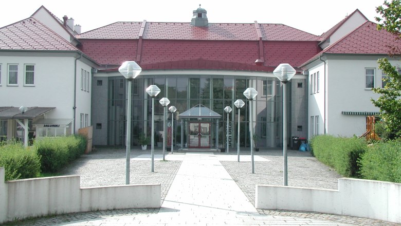 Kulturhaus, © Stadtgemeinde Schrems Eingang eines modernen Kulturhauses mit Glasfassade und roten Dächern.