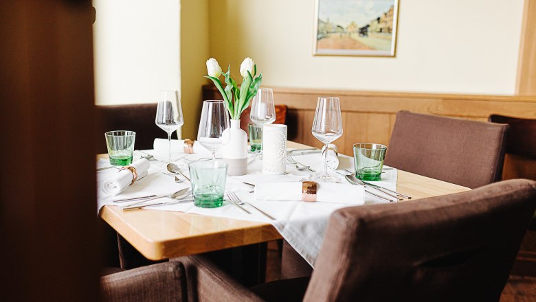 Einladendes Gasthaus mit regionaler Waldviertler Küche, © Niederösterreich Werbung/Mara Hohla Ein elegant gedeckter Tisch in einem Gasthaus mit Gläsern, Besteck und weißen Tulpen in einer Vase.