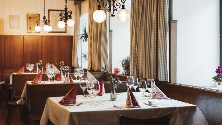 Einkehren in Krumbach, © Niederösterreich Werbung/David Schreiber Gemütliches Restaurant mit gedeckten Tischen, Weingläsern und Blumenvasen.