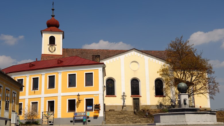 Hauptplatz - Kirche, © Gerhard Wanko Kirche mit gelber Fassade und Turm mit rotem Dach auf einem Hauptplatz.