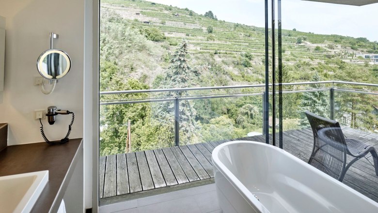 Steigenberger Krems Weinbergsuite, Bad, © Steigenberger Hotel and Spa, Gregor Titze Badezimmer mit freistehender Badewanne und Blick auf Weinberge.