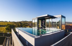 Dachpool, © Althof Retz Dachpool mit Glaswänden auf einem modernen Gebäude, umgeben von Landschaft.