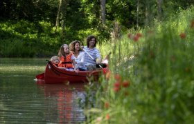 Kanufahren im Wasserpark, © DIE GARTEN TULLN Familie im Kanu auf einem Fluss im Grünen.
