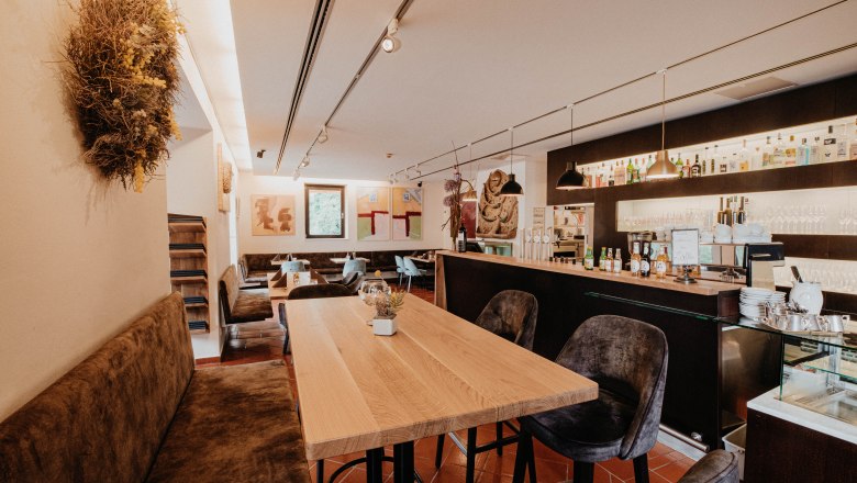 Restaurant Der Löffler, © Nixxpixx.com Innenansicht eines modernen Restaurants mit Holztischen, Bar und Kunstwerken an den Wänden.