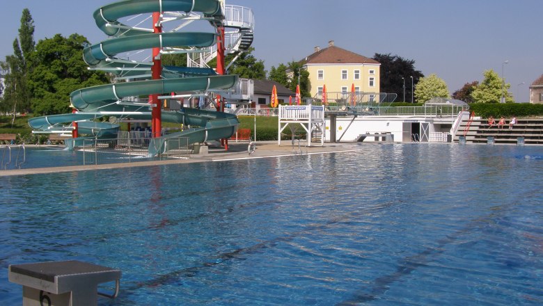Freibad Schwechat, © Stadtgemeinde Schwechat Freibad mit großer Wasserrutsche und Schwimmbecken.