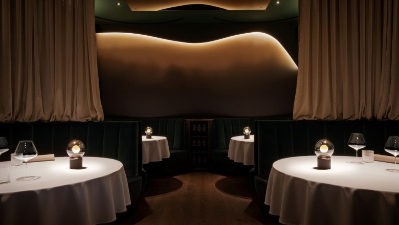 Restaurant, © Laura Thiesbrummel Elegantes Restaurant mit runden Tischen, weißen Tischdecken und gedämpfter Beleuchtung.