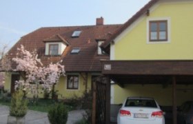Gästehaus, © Fam. Brandl-Göstl Gelbes Gästehaus mit blühendem Baum und zwei geparkten Autos.