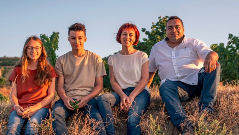 Familie Berger, © Weingut und Gästehaus Berger Vier Personen sitzen auf einem Feld im Sonnenuntergang.
