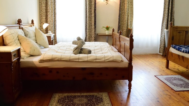 Gemütlich Schlafen im Raxkönig, © Reinhard Maurer Gemütliches Schlafzimmer mit Holzbett, Nachttischen und dekorativen Handtüchern auf dem Bett.