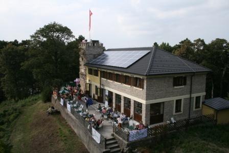 Höllensteinhaus - ein Haus der Naturfreunde, © NATURFREUNDE Wien Höllensteinhaus mit Terrasse und Solarpanelen auf dem Dach, umgeben von Bäumen.