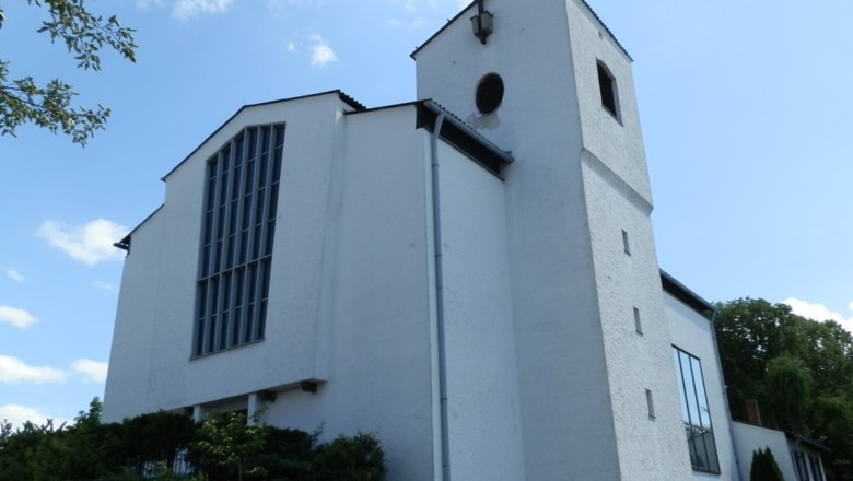 Wartmannstetten, © Gemeinde Wartmannstetten Weiße Kirche mit Turm und Kreuz vor blauem Himmel.